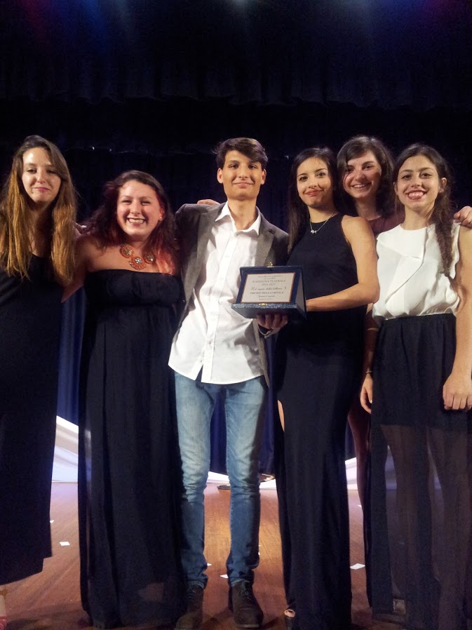 Cinque ragazze e un ragazzo vestiti eleganti, membri della compagnia teatrale dei Fuori Scena, reggono il premio della critica vinto alla rassegna teatrale di Mesero, in provincia di Milano.